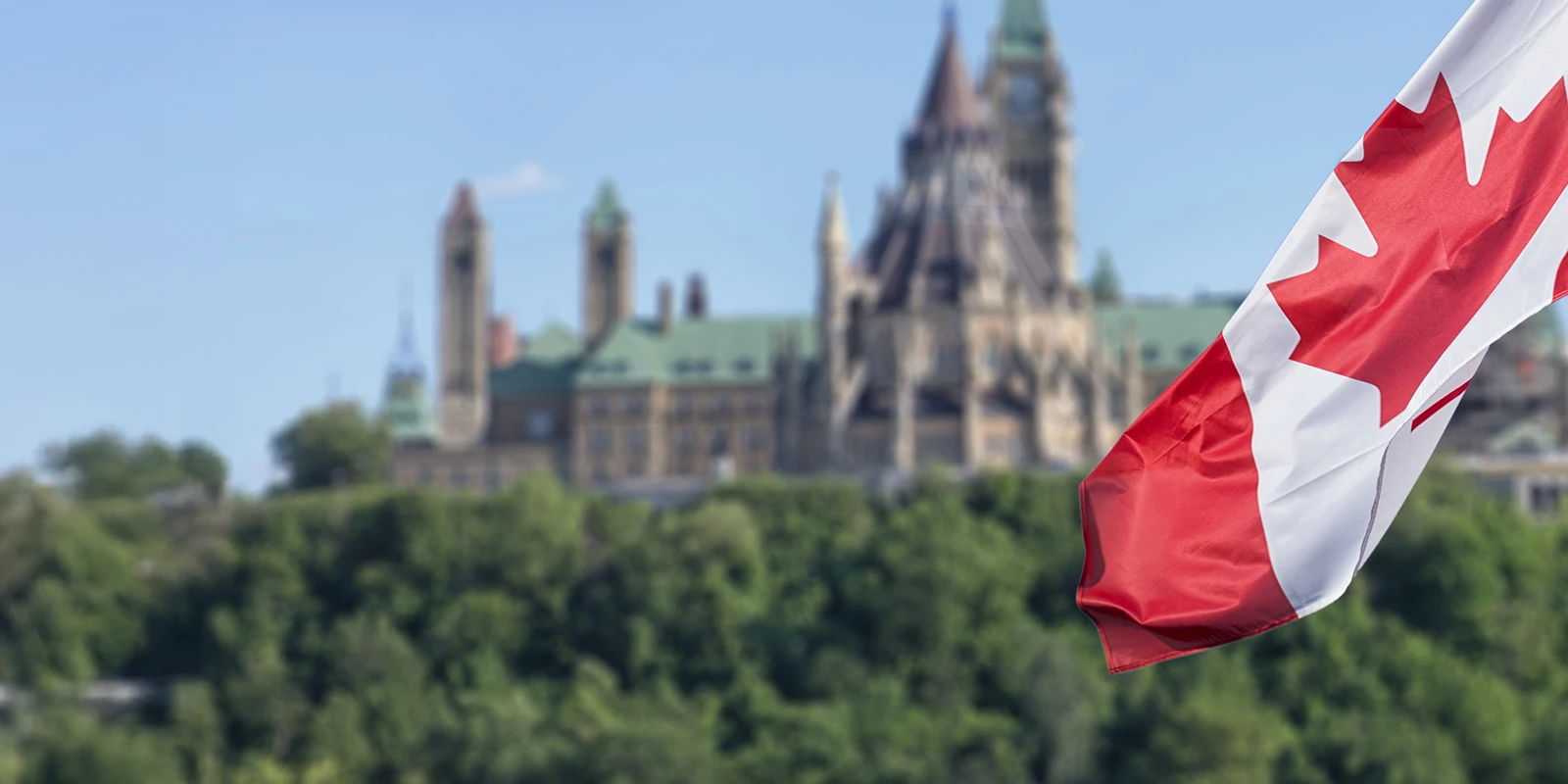 Drapeau canadien devant le bâtiment du Parlement.
