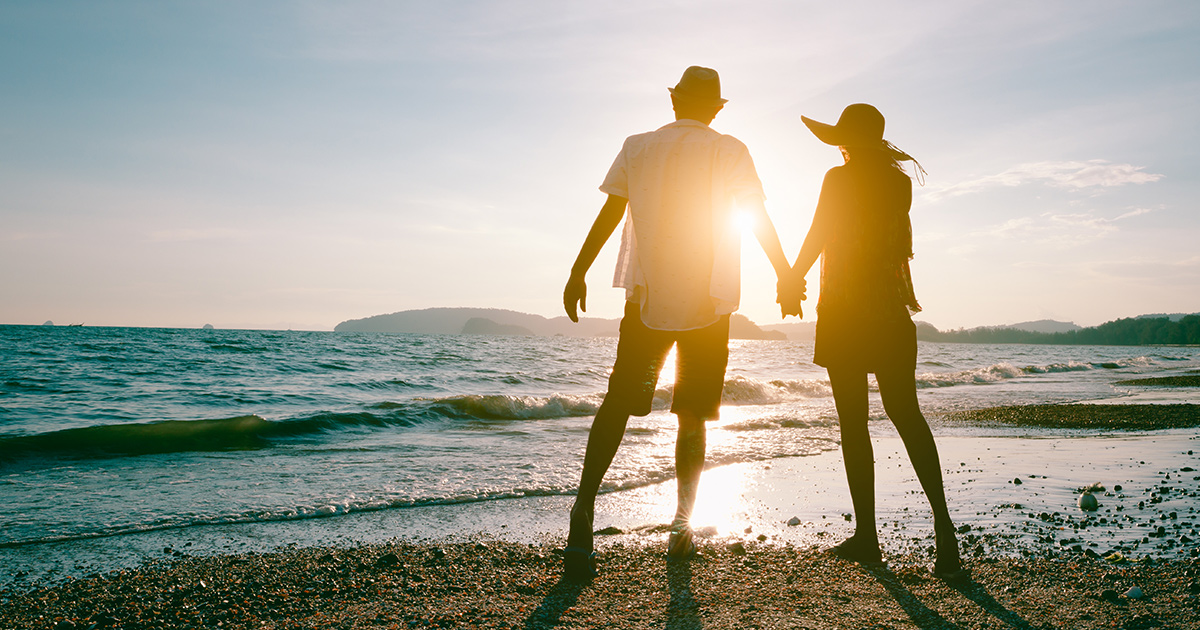 Couple d'âge moyen profitant d'une belle promenade au coucher du soleil sur la plage