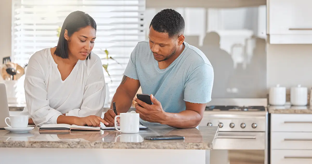 Un couple calcule ses dépenses mensuelles et révise des documents ensemble à la maison.