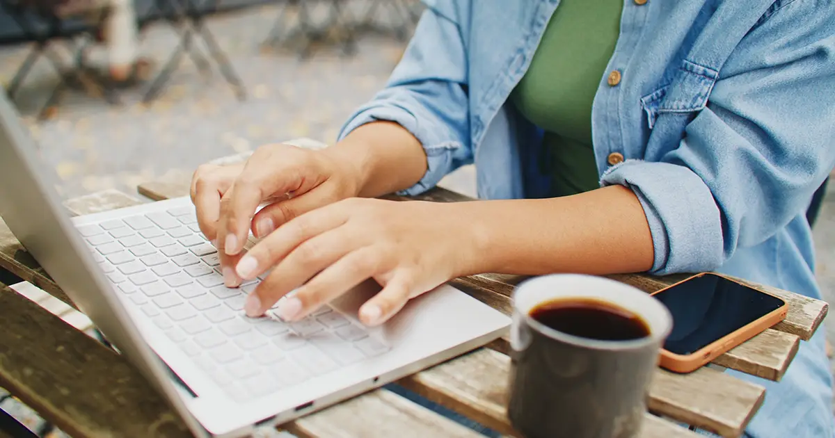 une femme tape un message sur son ordinateur portable alors qu'elle est assise dans un café