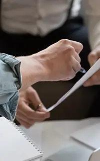 Des mains échangent des documents lors d’une réunion financière au bureau