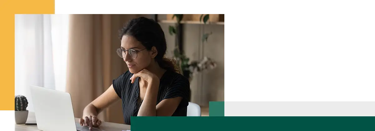 Jeune femme concentrée, assise à son bureau à la maison, travaillant