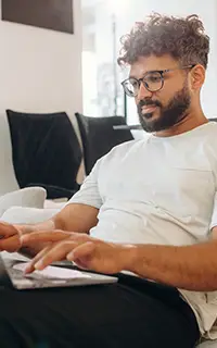 L'homme, assis sur le canapé avec son ordinateur portable, se trouve dans le salon moderne de sa maison.