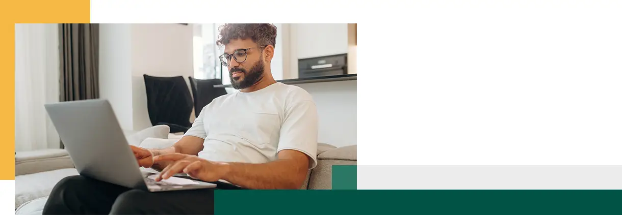 L'homme, assis sur le canapé avec son ordinateur portable, se trouve dans le salon moderne de sa maison.