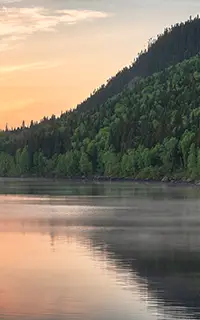 Magnifique lever de soleil sur un lac fumant entouré de montagnes boisées au Québec, Canada