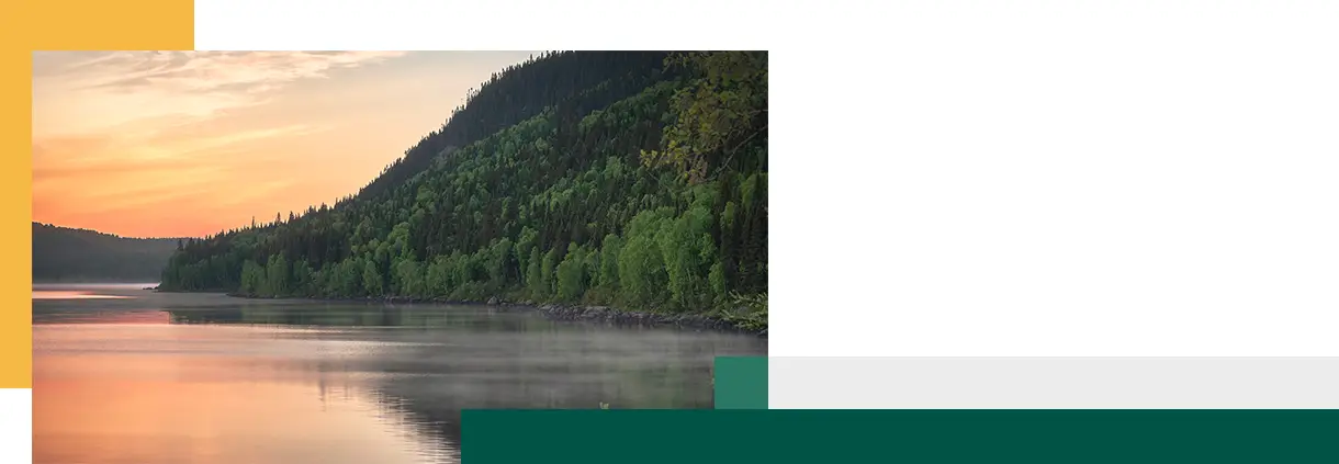 Magnifique lever de soleil sur un lac fumant entouré de montagnes boisées au Québec, Canada