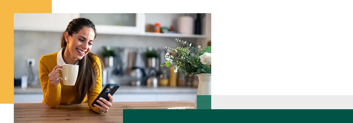 Une personne utilise son smartphone tout en étant assise au comptoir de la cuisine