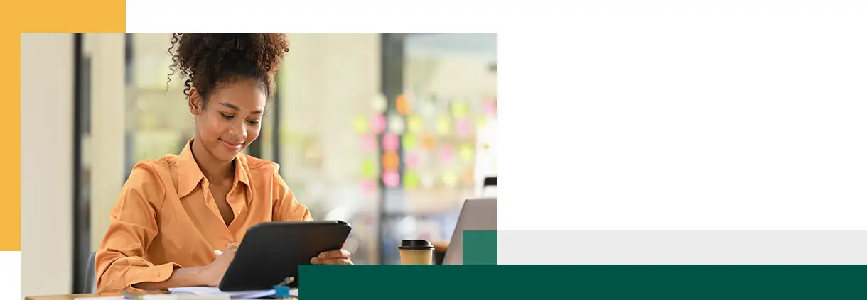 Une employée consulte des informations en ligne sur une tablette à son bureau.
