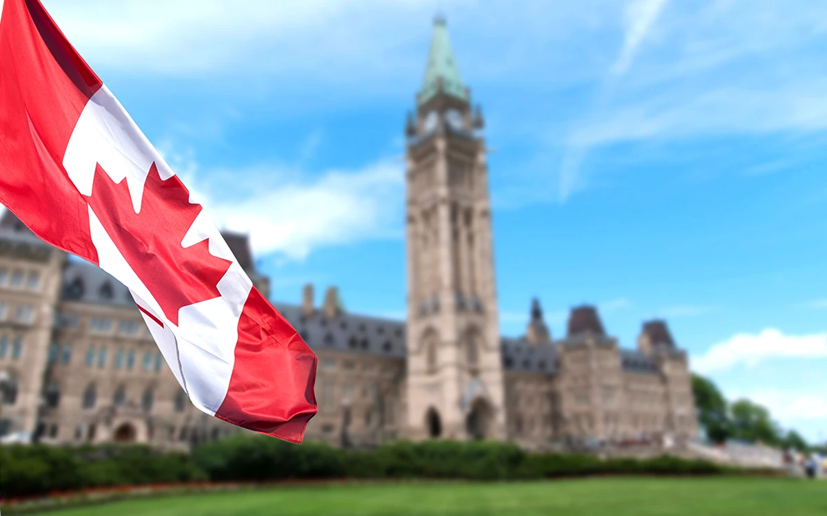 Drapeau canadien flottant devant le Parlement canadien