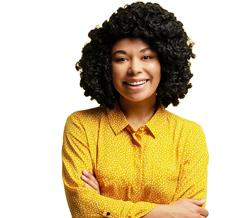 Personne souriante avec des cheveux courts et bouclés, portant une chemise jaune à pois, les bras croisés sur un fond clair uni.