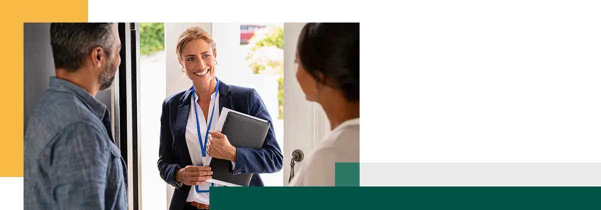 Un homme et une femme accueillent l'agent à leur domicile, debout près de la porte.