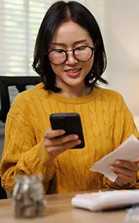 Femme asiatique calculant ses dépenses et ses paiements de factures avec un smartphone