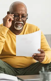 Travailler sur des documents en portant des lunettes, assis sur le canapé à la maison