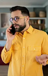 Un homme en chemise jaune au téléphone, dans une conversation tendue.
