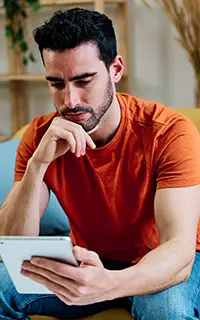 Homme pensif utilisant une tablette sur le canapé
