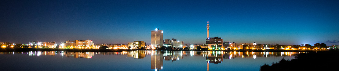 Night view of downtown Moncton with reflection in a body of water.